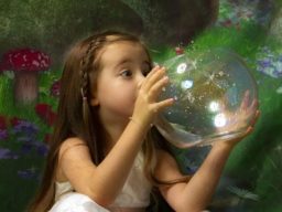 Young girl looking at fairies in a bowl with fantasy background