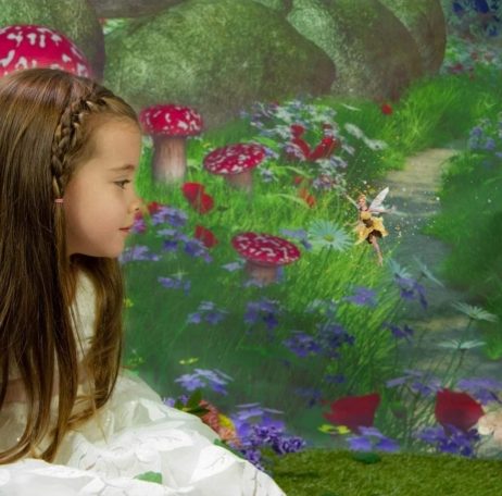 Young girl with antasy forest behind talking to a fairy