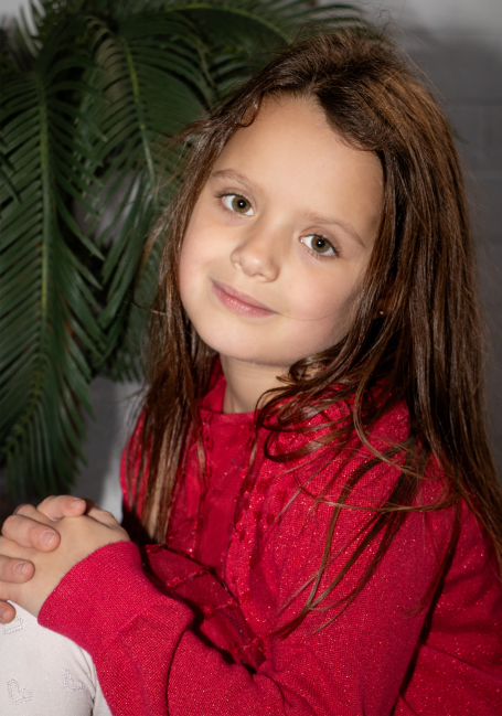 young girl in red dress and red cardigan looking at camera