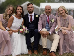 Image of family posing for picture sat on bales of hay