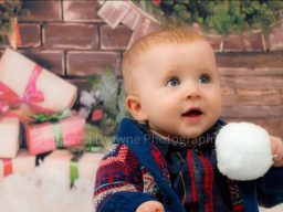 Very young boy holding snowball with Christmas background