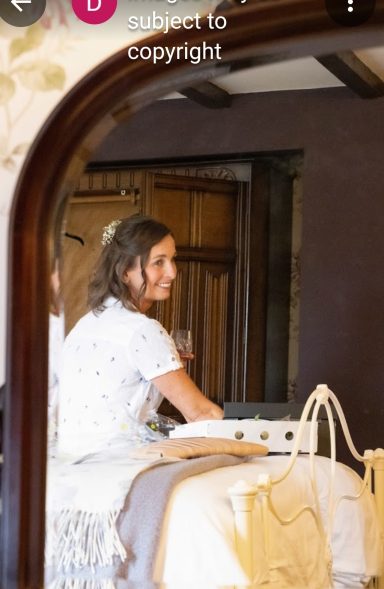 Bride sat edge of bed reflected in mirror