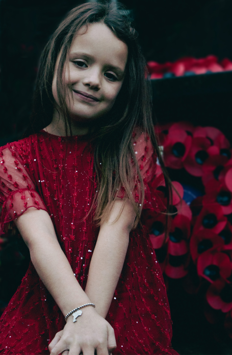 Young girl in red dress poppy wreathes in background